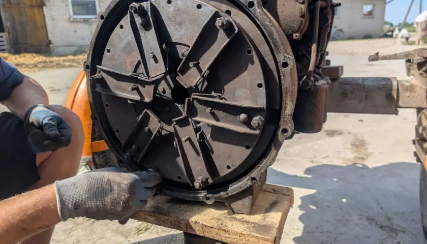 Regulacja sprzęgła w C330. Mechanik w rękawiczkach dokręca śruby w tarczy sprzęgła Ursusa C330.