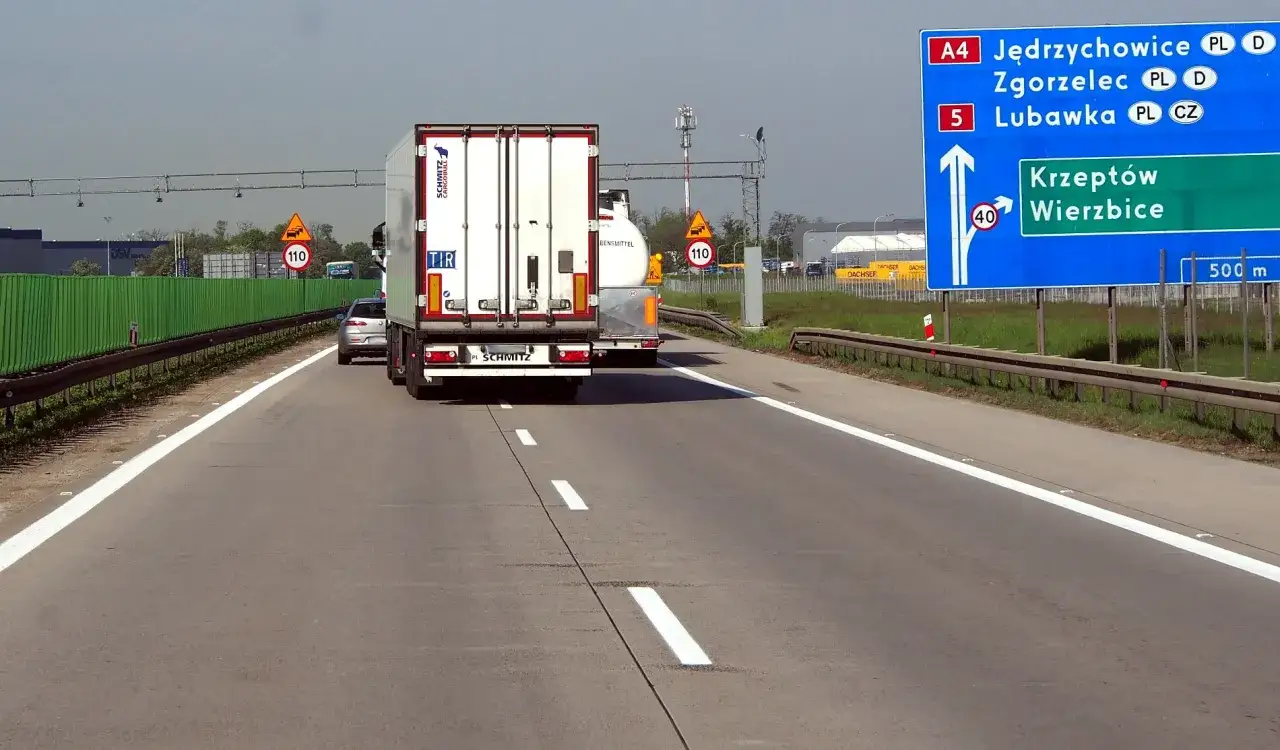 Na autostradzie A4, ciężarówka jedzie za innymi pojazdami. Znak informuje o zakazie wyprzedzania ciężarówek od kiedy?