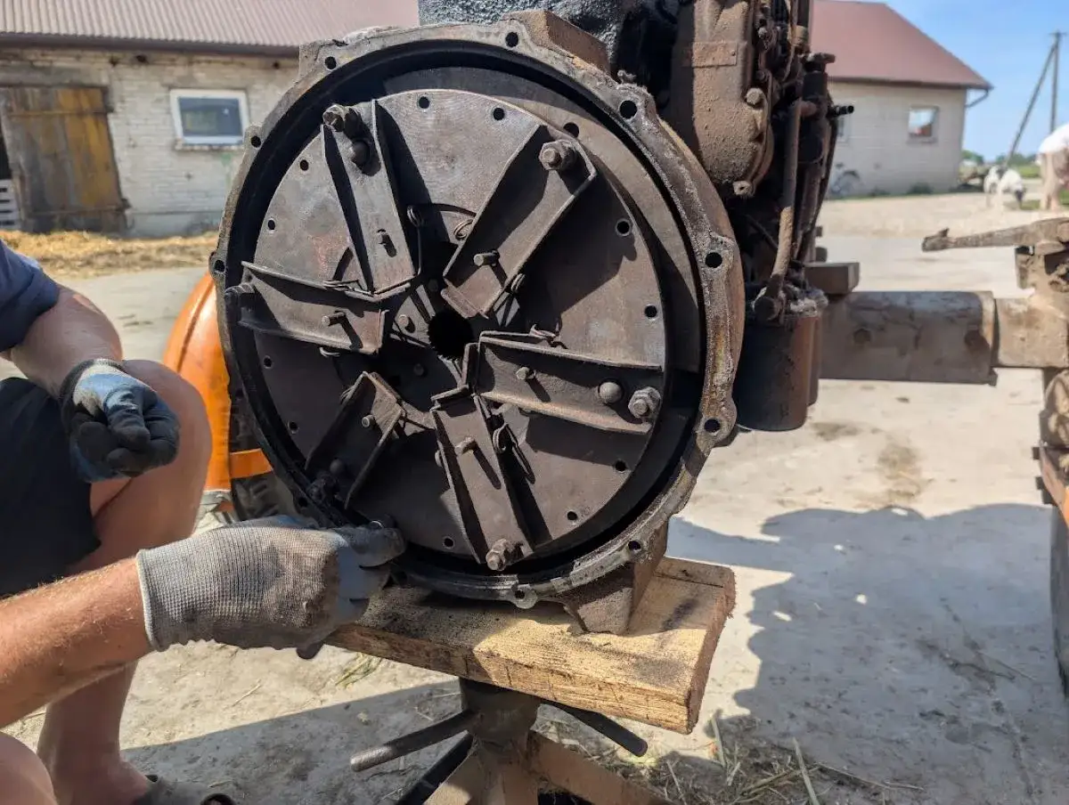 Regulacja sprzęgła w C330. Mechanik w rękawiczkach dokręca śruby docisku sprzęgła.
